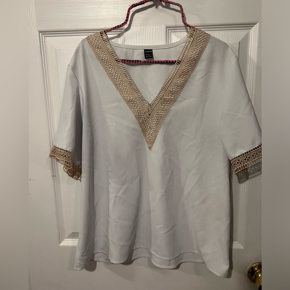 White blouse with gold accent around the sleeves and front